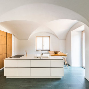 Ispirazione per un cucina con isola centrale mediterraneo con lavello integrato, ante lisce, ante in legno scuro, top bianco e soffitto a volta