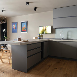 Immagine di una cucina contemporanea di medie dimensioni con lavello a doppia vasca, ante lisce, ante grigie, pavimento in legno massello medio, penisola, top grigio, top in marmo e pavimento marrone