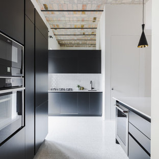 Immagine di una grande cucina design con lavello sottopiano, ante lisce, ante nere, paraspruzzi bianco, paraspruzzi con piastrelle diamantate, elettrodomestici da incasso, pavimento grigio e top bianco