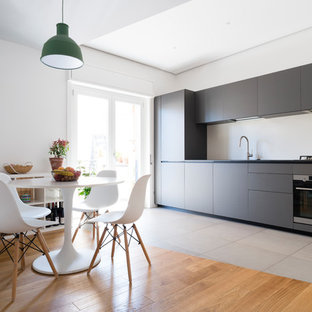 Ispirazione per una cucina minimal con ante lisce, ante grigie, elettrodomestici in acciaio inossidabile, nessuna isola, pavimento grigio e top nero