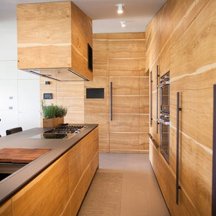 Idee per una cucina minimal con ante lisce, ante in legno chiaro, paraspruzzi nero, elettrodomestici da incasso e pavimento beige