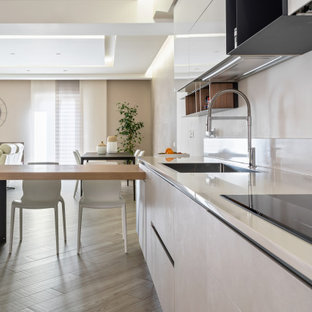 Immagine di una cucina contemporanea di medie dimensioni con lavello da incasso, ante lisce, ante bianche, paraspruzzi bianco, elettrodomestici da incasso, pavimento in legno massello medio, penisola, pavimento beige e top bianco