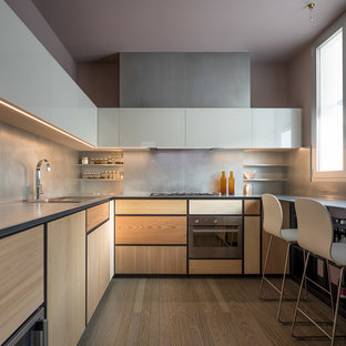 Foto di una cucina a L design con ante in legno chiaro, paraspruzzi grigio, lavello sottopiano, ante lisce, elettrodomestici in acciaio inossidabile, pavimento in legno massello medio, pavimento marrone e top grigio