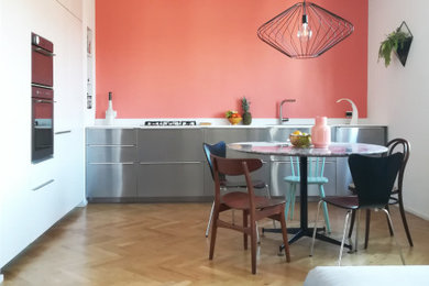 Ispirazione per una cucina design con ante lisce, ante bianche, elettrodomestici in acciaio inossidabile, parquet chiaro, nessuna isola, pavimento beige e top bianco