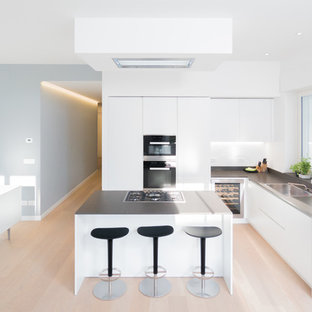 Ispirazione per una grande cucina minimal con lavello a vasca singola, ante lisce, ante bianche, pavimento in legno massello medio e isola