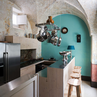 Ispirazione per una cucina ad U mediterranea con ante lisce, ante in legno chiaro, top in acciaio inossidabile, paraspruzzi multicolore, elettrodomestici in acciaio inossidabile e penisola