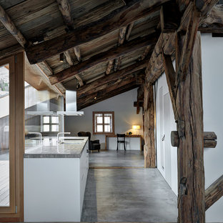 Immagine di una grande cucina rustica con ante lisce, ante bianche, pavimento in cemento, pavimento grigio, lavello sottopiano, paraspruzzi a finestra e top grigio