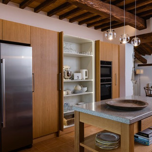 Ispirazione per un cucina con isola centrale mediterraneo con ante lisce, ante in legno scuro, elettrodomestici in acciaio inossidabile, pavimento marrone e top grigio