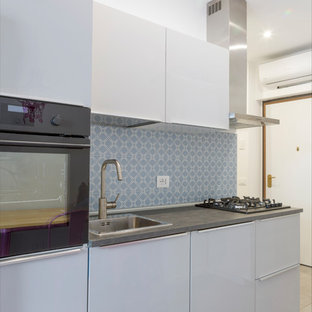 Foto di una piccola cucina lineare contemporanea con ante lisce, ante bianche, paraspruzzi blu, elettrodomestici neri e top grigio