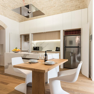 Ispirazione per una grande cucina mediterranea con ante lisce, ante bianche, paraspruzzi bianco, elettrodomestici in acciaio inossidabile, pavimento in legno massello medio, pavimento marrone, lavello sottopiano, isola e top bianco