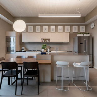 Idee per una cucina parallela contemporanea con ante lisce, ante in legno chiaro, elettrodomestici in acciaio inossidabile, pavimento in cemento, isola, pavimento grigio, top nero e soffitto in legno