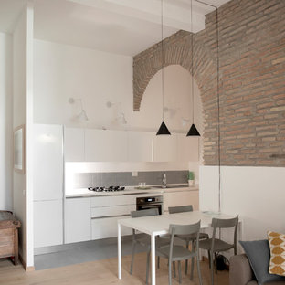 Esempio di una cucina mediterranea con lavello a doppia vasca, ante lisce, ante bianche, top in laminato, paraspruzzi grigio, paraspruzzi in gres porcellanato, elettrodomestici bianchi, pavimento in gres porcellanato, top bianco, nessuna isola e pavimento grigio