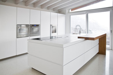 Immagine di un'ampia cucina design con lavello da incasso, ante lisce, ante bianche, top in superficie solida e elettrodomestici in acciaio inossidabile