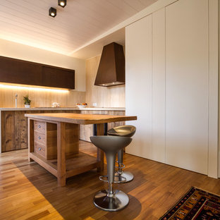 Immagine di una cucina mediterranea con ante lisce, ante in legno scuro, paraspruzzi beige, paraspruzzi in legno, pavimento in legno massello medio e pavimento marrone
