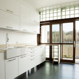 Idee per una cucina lineare minimal di medie dimensioni con pavimento in gres porcellanato, lavello stile country, ante lisce, ante bianche, top in legno, pavimento nero e top marrone