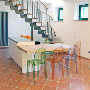 Zweizeilige, Mittelgroße Moderne Wohnküche mit Doppelwaschbecken, flächenbündigen Schrankfronten, weißen Schränken, Edelstahl-Arbeitsplatte, Küchenrückwand in Schwarz, Küchengeräten aus Edelstahl, Terrakottaboden, Kücheninsel und rosa Boden in Sonstige