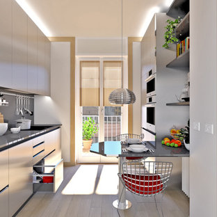 Ispirazione per una piccola cucina lineare contemporanea chiusa con lavello sottopiano, ante lisce, ante in acciaio inossidabile, top in quarzo composito, paraspruzzi nero, elettrodomestici in acciaio inossidabile, pavimento in gres porcellanato, penisola, pavimento marrone e top nero
