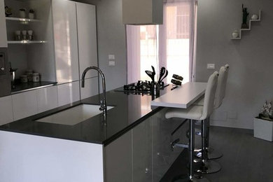 Foto di una cucina moderna con lavello sottopiano, ante bianche, top in quarzite, elettrodomestici in acciaio inossidabile e top grigio
