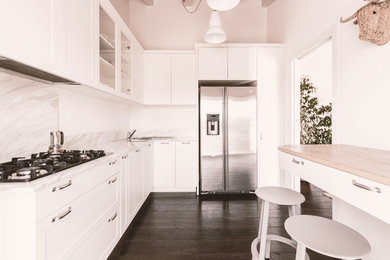 ミラノにある高級な中くらいなコンテンポラリースタイルのおしゃれなキッチン (ダブルシンク、落し込みパネル扉のキャビネット、白いキャビネット、大理石カウンター、白いキッチンパネル、大理石のキッチンパネル、シルバーの調理設備、濃色無垢フローリング、茶色い床、白いキッチンカウンター) の写真
