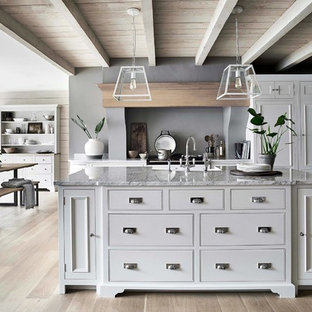 Immagine di una grande cucina tradizionale con ante bianche, lavello stile country, ante a filo, top in marmo, paraspruzzi grigio, parquet chiaro e top grigio