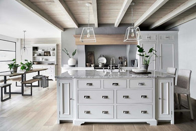Immagine di una grande cucina tradizionale con ante bianche, lavello stile country, ante a filo, top in marmo, paraspruzzi grigio, parquet chiaro e top grigio