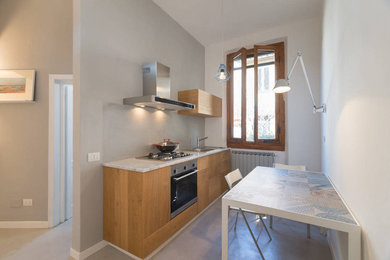 Immagine di una piccola cucina abitabile contemporanea con ante in legno chiaro e top in marmo