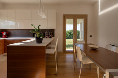Immagine di una cucina minimalista con ante in legno bruno e top bianco