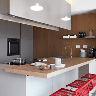 Esempio di una cucina parallela minimal con lavello integrato, ante lisce, ante grigie, top in legno, elettrodomestici in acciaio inossidabile, penisola, top marrone, paraspruzzi marrone e paraspruzzi a finestra