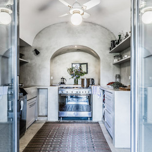 Ispirazione per una cucina ad U mediterranea di medie dimensioni con lavello integrato, ante in stile shaker, ante bianche, paraspruzzi grigio, elettrodomestici in acciaio inossidabile, nessuna isola, pavimento grigio e top grigio