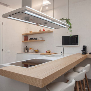 Foto di una cucina a L contemporanea con lavello sottopiano, ante lisce, ante bianche, penisola e top bianco