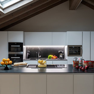 Foto di una cucina minimal di medie dimensioni con lavello integrato, ante lisce, ante bianche, paraspruzzi nero, elettrodomestici da incasso e top nero
