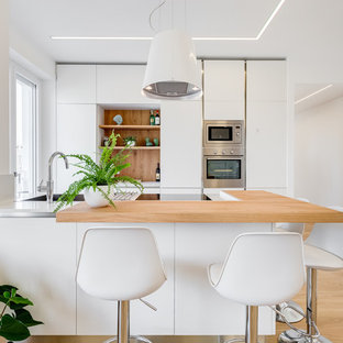 Idee per una cucina parallela contemporanea con ante lisce, ante bianche, top in legno, elettrodomestici in acciaio inossidabile, parquet chiaro, pavimento marrone e top marrone