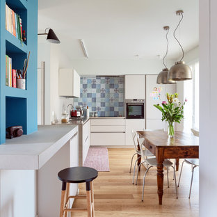 Idee per una cucina bohémian con ante lisce, ante bianche, paraspruzzi multicolore, elettrodomestici in acciaio inossidabile, parquet chiaro e pavimento beige