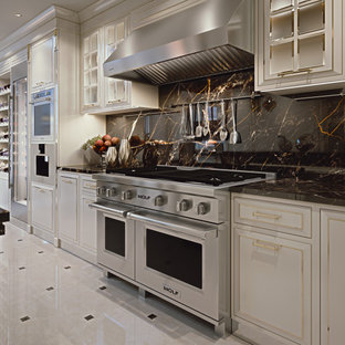 Modelo de cocina en L y bandeja, contemporánea, de tamaño medio, cerrada, con fregadero bajoencimera, armarios con paneles lisos, puertas de armario blancas, encimera de mármol, salpicadero negro, salpicadero de mármol, electrodomésticos de acero inoxidable, suelo de mármol, una isla, suelo blanco y encimeras negras
