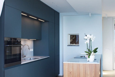 Esempio di una cucina minimal di medie dimensioni con lavello sottopiano, ante a filo, ante blu, top in marmo, paraspruzzi in marmo, elettrodomestici in acciaio inossidabile, parquet chiaro, top bianco e soffitto ribassato