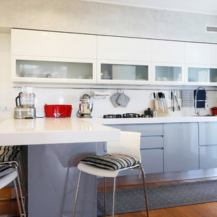 Ispirazione per una cucina a L design con ante lisce, ante bianche, paraspruzzi bianco, penisola, top bianco e pavimento in legno massello medio