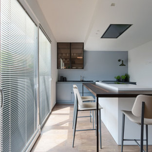 Ispirazione per una cucina contemporanea di medie dimensioni con lavello sottopiano, ante lisce, ante blu, top in legno, elettrodomestici da incasso, pavimento in legno massello medio, pavimento marrone e top marrone
