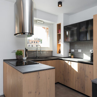 Immagine di una cucina ad U minimal con lavello integrato, ante lisce, ante in legno scuro, paraspruzzi grigio, paraspruzzi con piastrelle diamantate, penisola, pavimento grigio e top nero