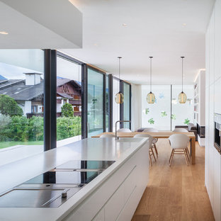 Idee per una cucina moderna con lavello integrato, ante lisce, ante bianche, elettrodomestici da incasso, pavimento in legno massello medio, pavimento beige e top bianco