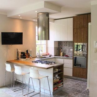 Ispirazione per una cucina ad U minimal di medie dimensioni con lavello sottopiano, ante lisce, ante in legno bruno, paraspruzzi con piastrelle in ceramica, pavimento in cemento, penisola, paraspruzzi grigio, elettrodomestici in acciaio inossidabile e pavimento grigio