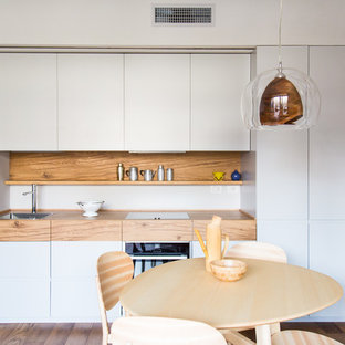 Immagine di una cucina minimalista di medie dimensioni con lavello da incasso, ante lisce, ante grigie, top in legno, paraspruzzi marrone, paraspruzzi in legno, pavimento in legno massello medio, nessuna isola e pavimento marrone