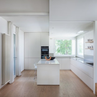 Esempio di una cucina minimalista chiusa e di medie dimensioni con paraspruzzi grigio, parquet chiaro, top grigio, ante lisce, ante bianche, elettrodomestici da incasso e pavimento beige