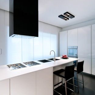 Esempio di un cucina con isola centrale design con lavello a doppia vasca, ante lisce, ante bianche, pavimento nero e top bianco