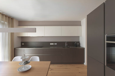 Moderne Küche mit Unterbauwaschbecken, Quarzit-Arbeitsplatte, braunem Holzboden und braunem Boden in Sonstige