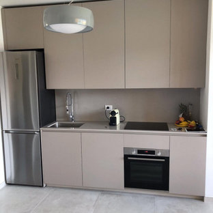 Photo of a small modern single-wall open plan kitchen in Milan with an undermount sink, flat-panel cabinets, beige cabinets, laminate benchtops, beige splashback, black appliances, ceramic floors, no island, grey floor and beige benchtop.