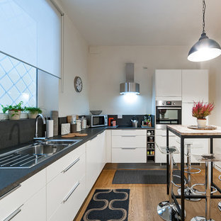 Idee per una cucina a L minimal di medie dimensioni con lavello da incasso, ante lisce, ante bianche, elettrodomestici in acciaio inossidabile, pavimento in legno massello medio e nessuna isola