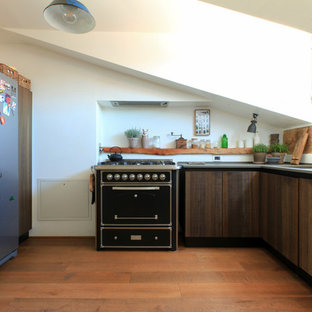 Esempio di una cucina ad U mediterranea chiusa con lavello a vasca singola, ante lisce, ante in legno bruno, paraspruzzi beige, pavimento in legno massello medio, nessuna isola, pavimento marrone e top grigio