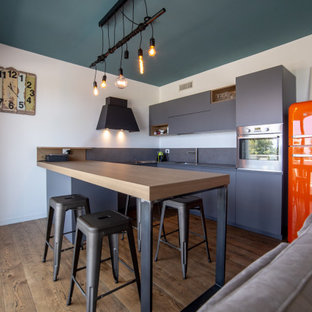 Ispirazione per una cucina industriale con lavello sottopiano, ante lisce, ante grigie, elettrodomestici colorati, parquet scuro, penisola, pavimento marrone e top grigio
