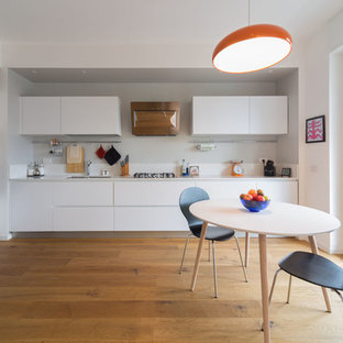 Foto di una cucina nordica di medie dimensioni con ante lisce, ante bianche, paraspruzzi bianco, elettrodomestici in acciaio inossidabile, pavimento in legno massello medio, nessuna isola, pavimento marrone e lavello sottopiano
