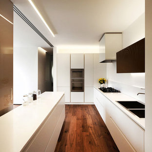 Design ideas for a large contemporary l-shaped open plan kitchen in Venice with an integrated sink, flat-panel cabinets, white cabinets, solid surface benchtops, white splashback, stainless steel appliances, a peninsula and dark hardwood floors.